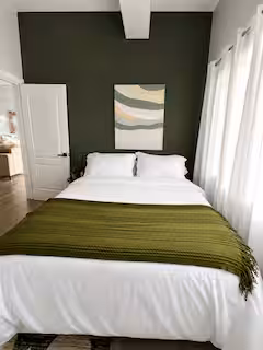 Master bedroom with olive accent wall and crisp white linens