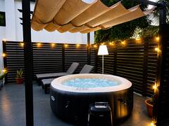 Pergola with private hot tub lit by warm string lights